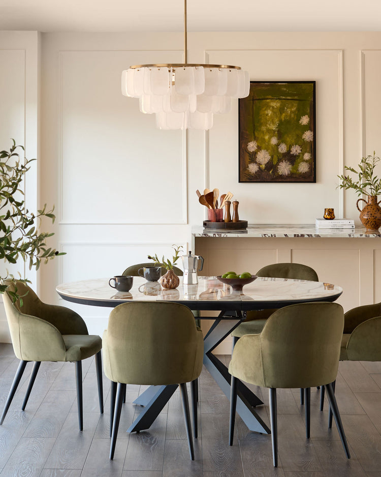 Hayden round extending dining table in natural ceramic with black metal base, seated with green upholstered chairs in modern dining room.