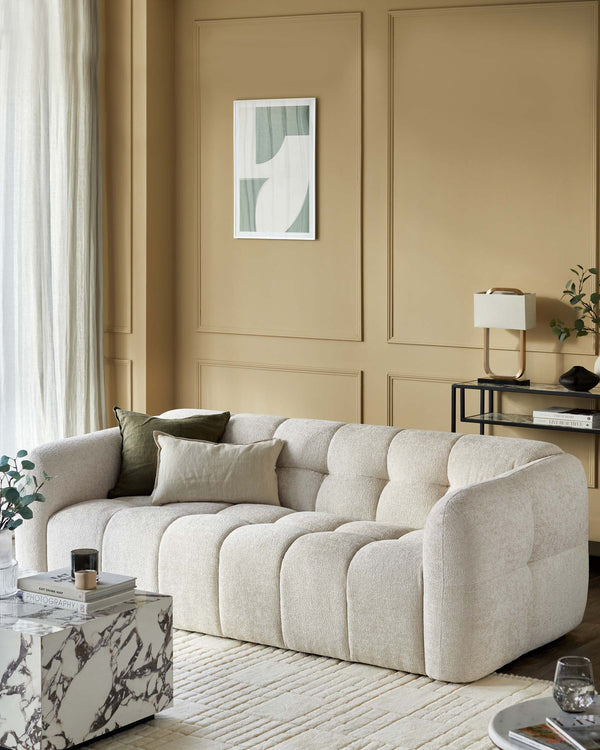 A beige bouclé sofa is complemented by a marble coffee table and a sleek black side table.