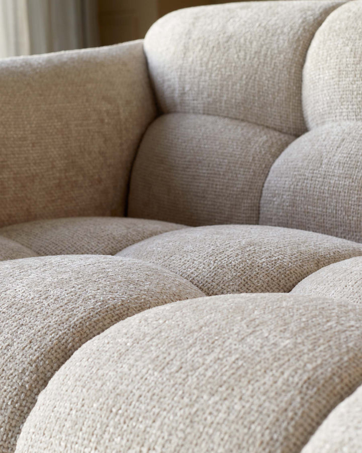 Close-up of a beige sofa with button-tufted cushions and a soft, textured fabric, inviting comfort and style.