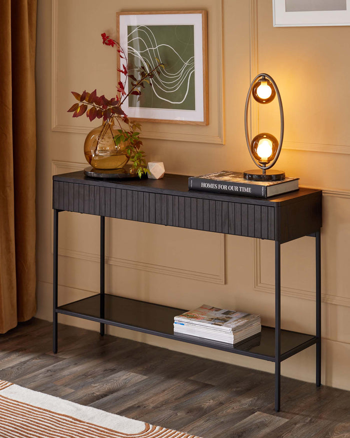 Dark wood console table with lower shelf, styled with lamp, vase and books. Modern hallway furniture.