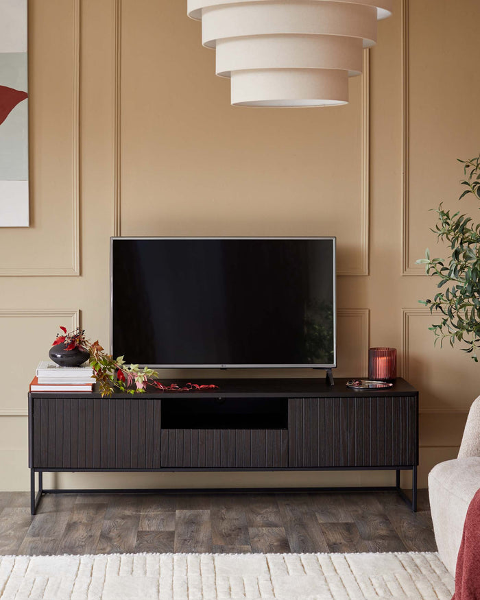 A dark wood TV stand with reeded door fronts, supporting a TV. Accessories complete the look.