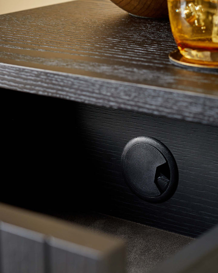 Close up of dark wood furniture featuring a cable management port and a textured surface.