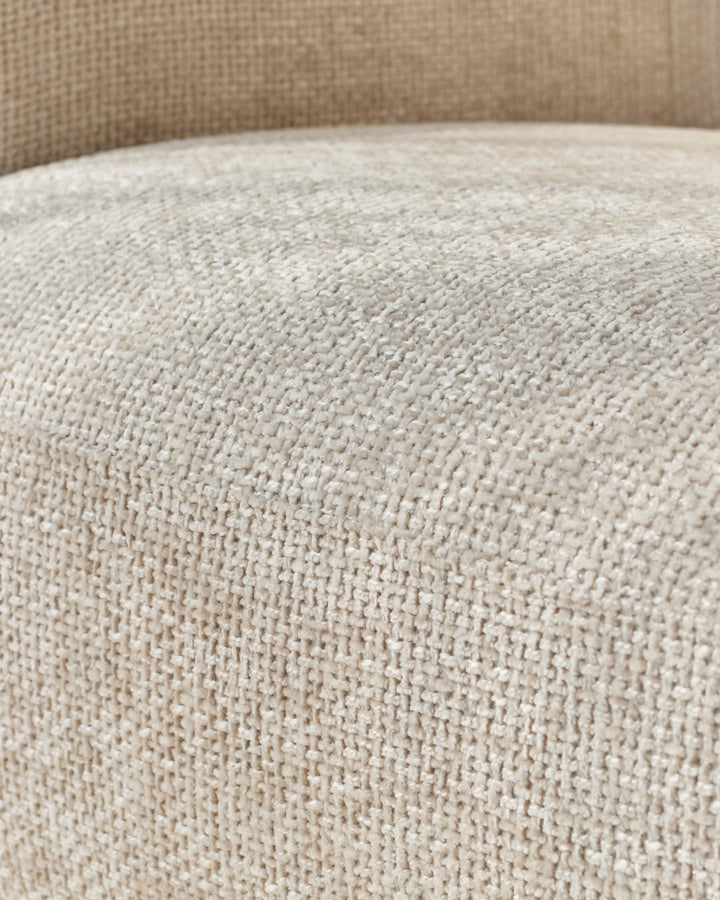 Close-up of textured, beige fabric on an upholstered chair or sofa, offering a tactile and neutral aesthetic.