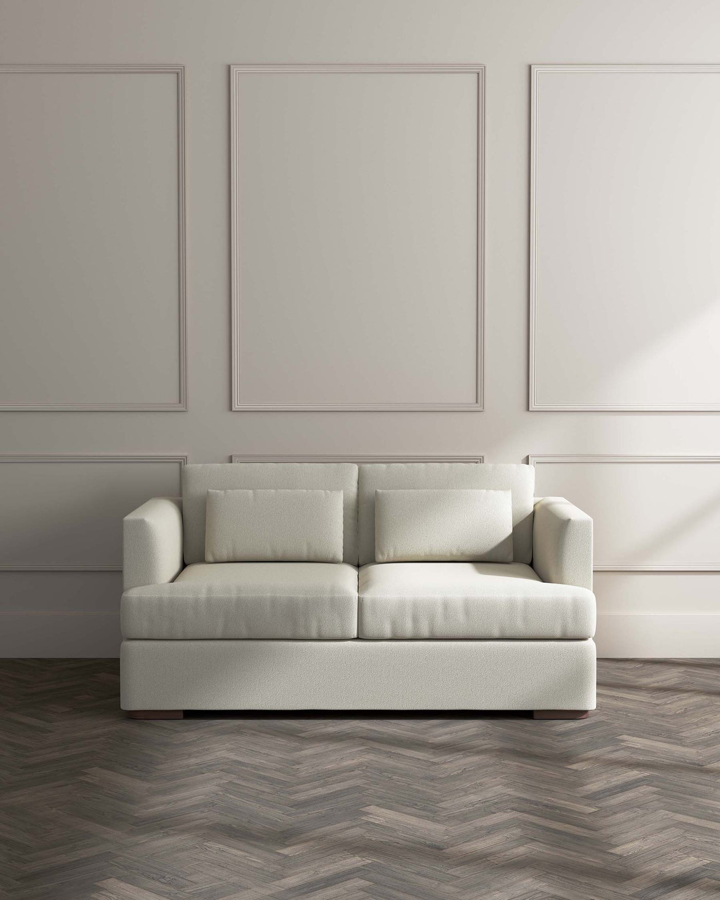 Modern minimalist three-seater sofa with clean lines, upholstered in a light grey fabric, standing on a dark herringbone parquet floor against a light grey wall with subtle panel detailing.