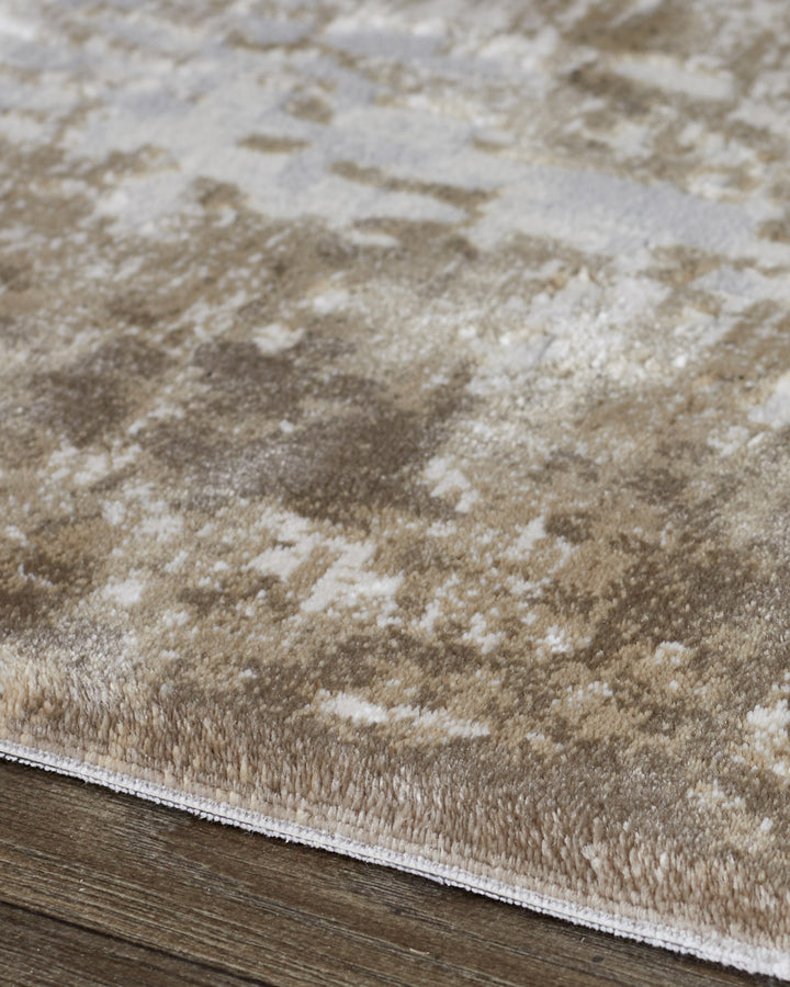 Distressed border medium textured rug in natural tones, showing cream and beige pattern detail on wooden floor.