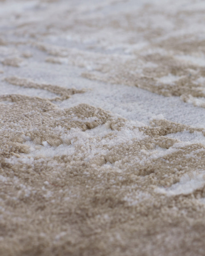 Close-up of textured rug surface showing natural beige and cream tones with distressed, wavy pattern detail.
