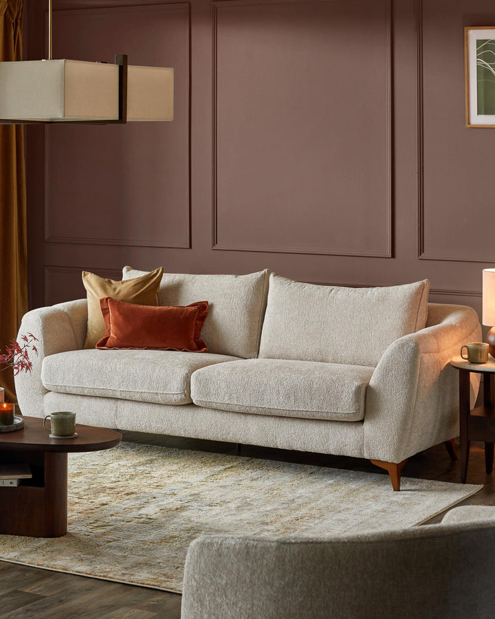Stylish living room with a comfy cream sofa, cushions, warm lighting, and a modern coffee table. Perfect for relaxation.