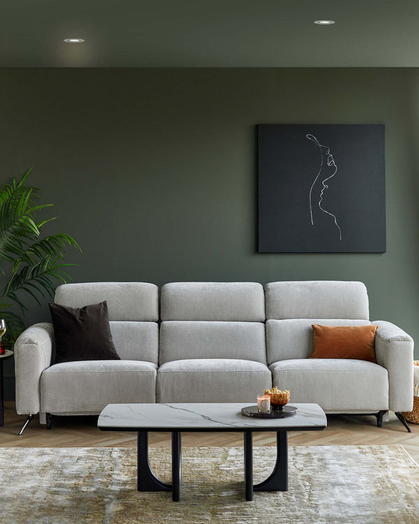 Grey sectional sofa with plush cushions and a decorative pillow, paired with a sleek marble-top coffee table on a patterned rug.