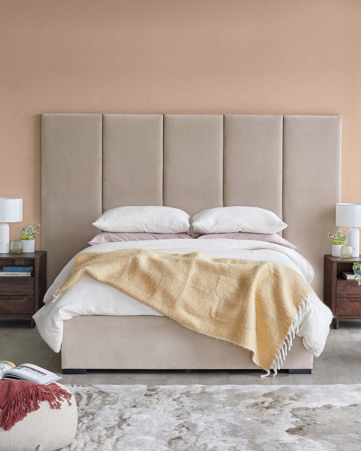 A modern upholstered bed with a tall headboard, soft pillows, a warm blanket, and stylish nightstands with lamps.