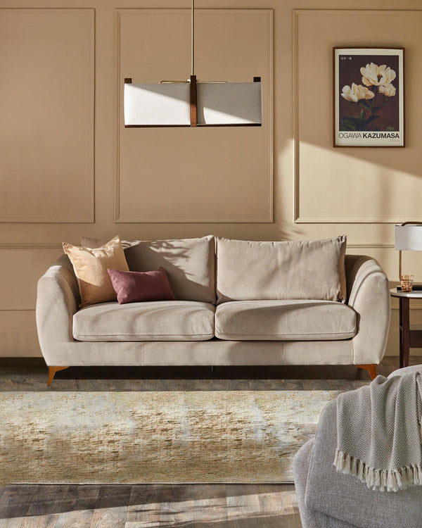 A neutral-toned sofa with cushions sits on a patterned rug, complemented by a side table and a hanging lamp.