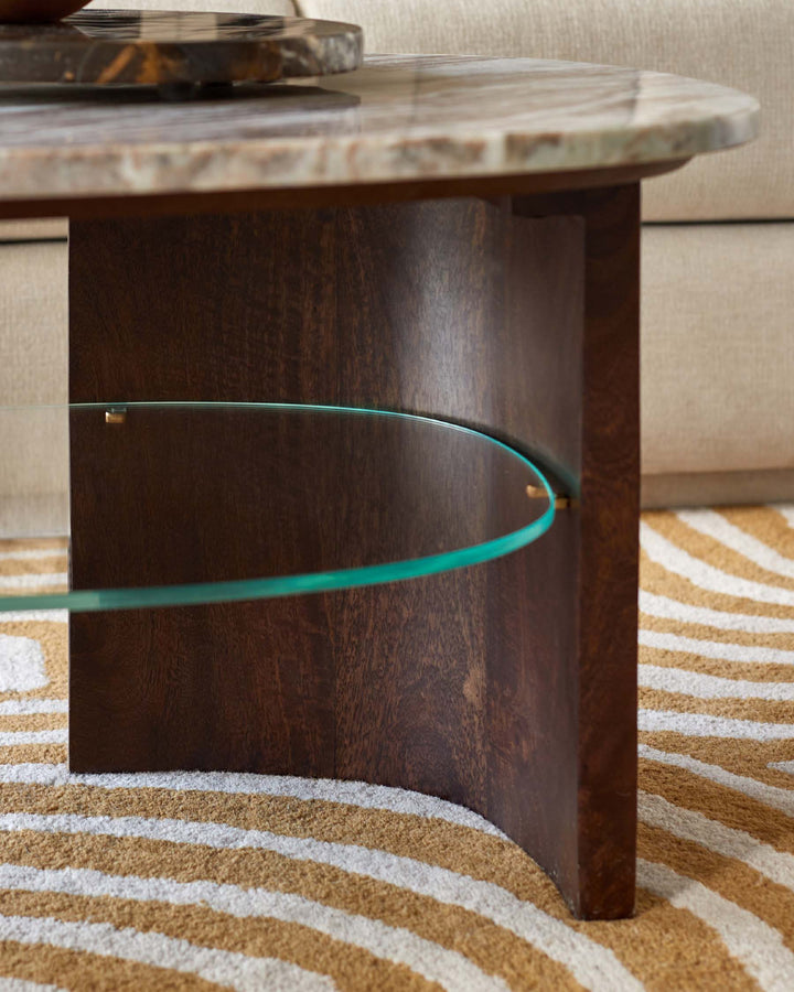A stylish coffee table with a marble top, dark wood base, and a curved glass shelf. Modern design with a touch of elegance.