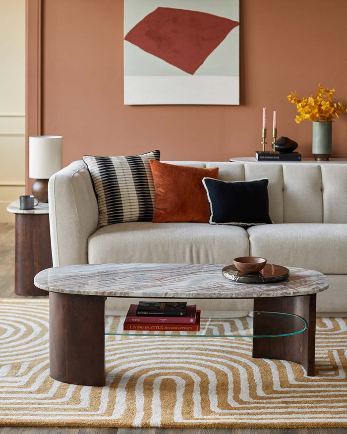 A living room display featuring a marble-topped coffee table, a neutral sofa with decorative cushions and a side table.