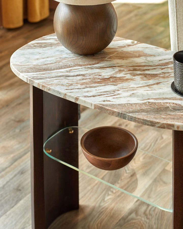 A marble-topped table with a wooden base and a glass shelf, featuring decorative wooden bowls.