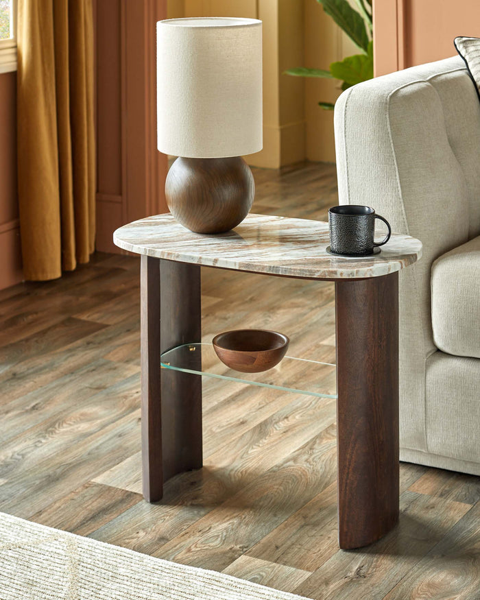 A stylish side table with a marble-effect top and dark wood legs. It features a lamp, mug and decorative bowl.