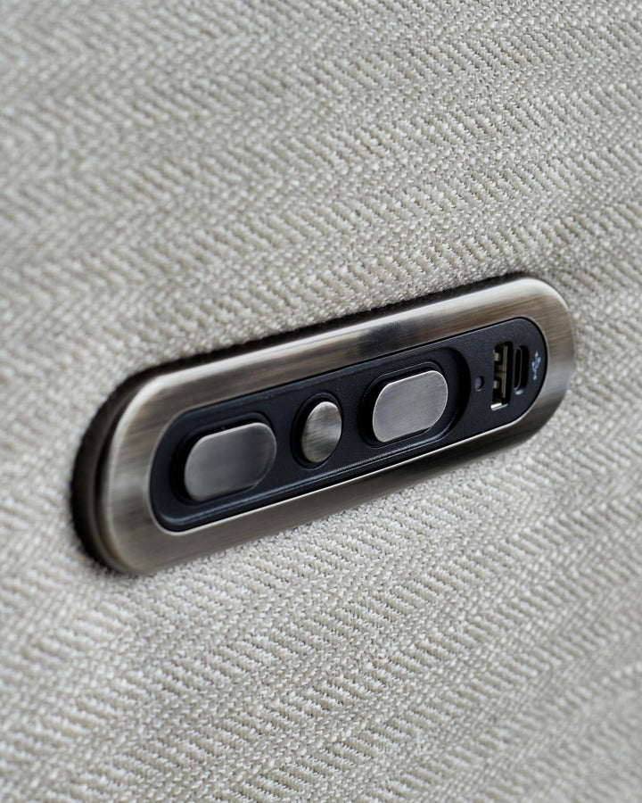 Close-up of a beige fabric sofa with bronze-coloured buttons and a USB port on the side.