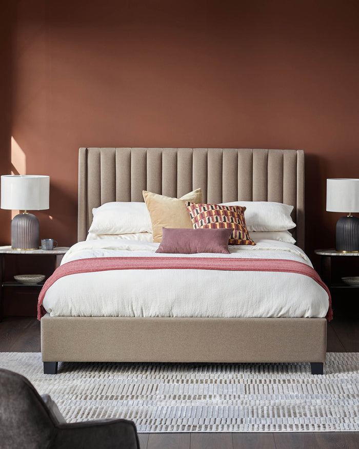 Bedroom with tan, vertically channelled headboard and base. Two side tables with lamps flank the bed. Cushions and a throw complete the look.