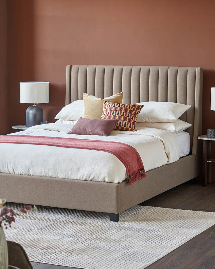 A stylish bedroom featuring a modern bed with a neutral-toned, vertically channelled headboard and a textured rug.