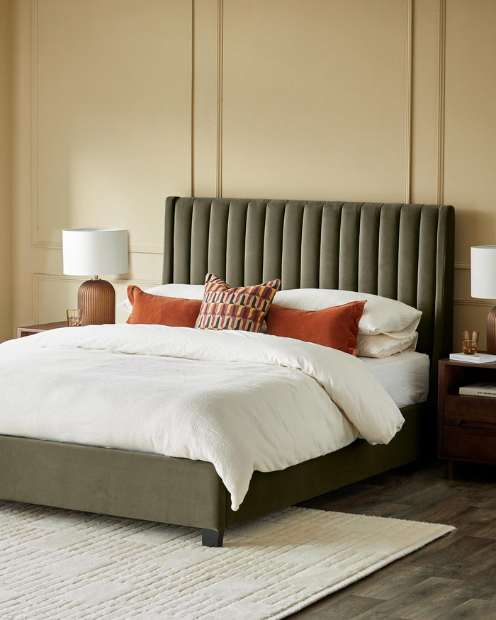 A beautifully made bed with a stylish headboard, bedside tables and lamps, on a wooden floor with a rug.