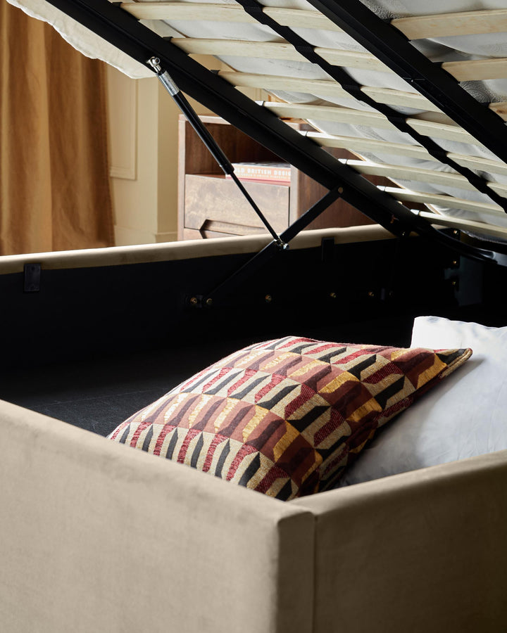 Lift up ottoman bed reveals storage space under a sprung slatted base. Pillows provide soft furnishings.