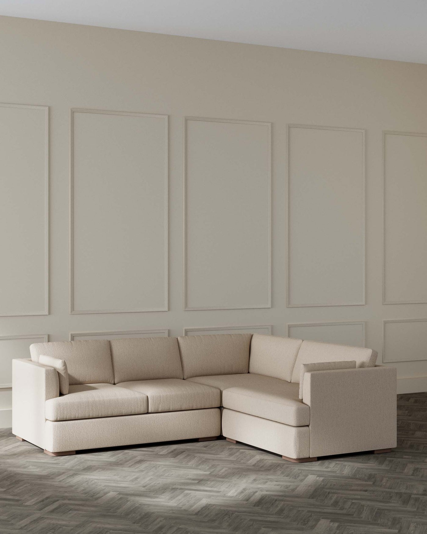 Beige modern corner sectional couch in a minimalist style room with panelled walls and herringbone pattern wood floor.