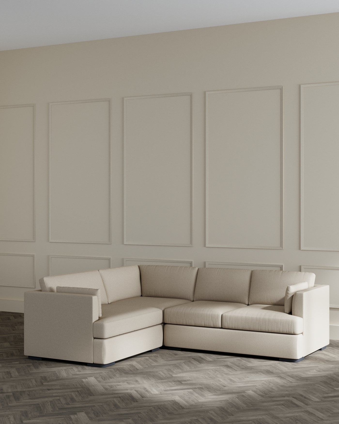 Modern beige upholstered L-shaped sectional sofa with clean lines, boxy frame, and low armrests against a neutral wall in a minimalist living room setting.