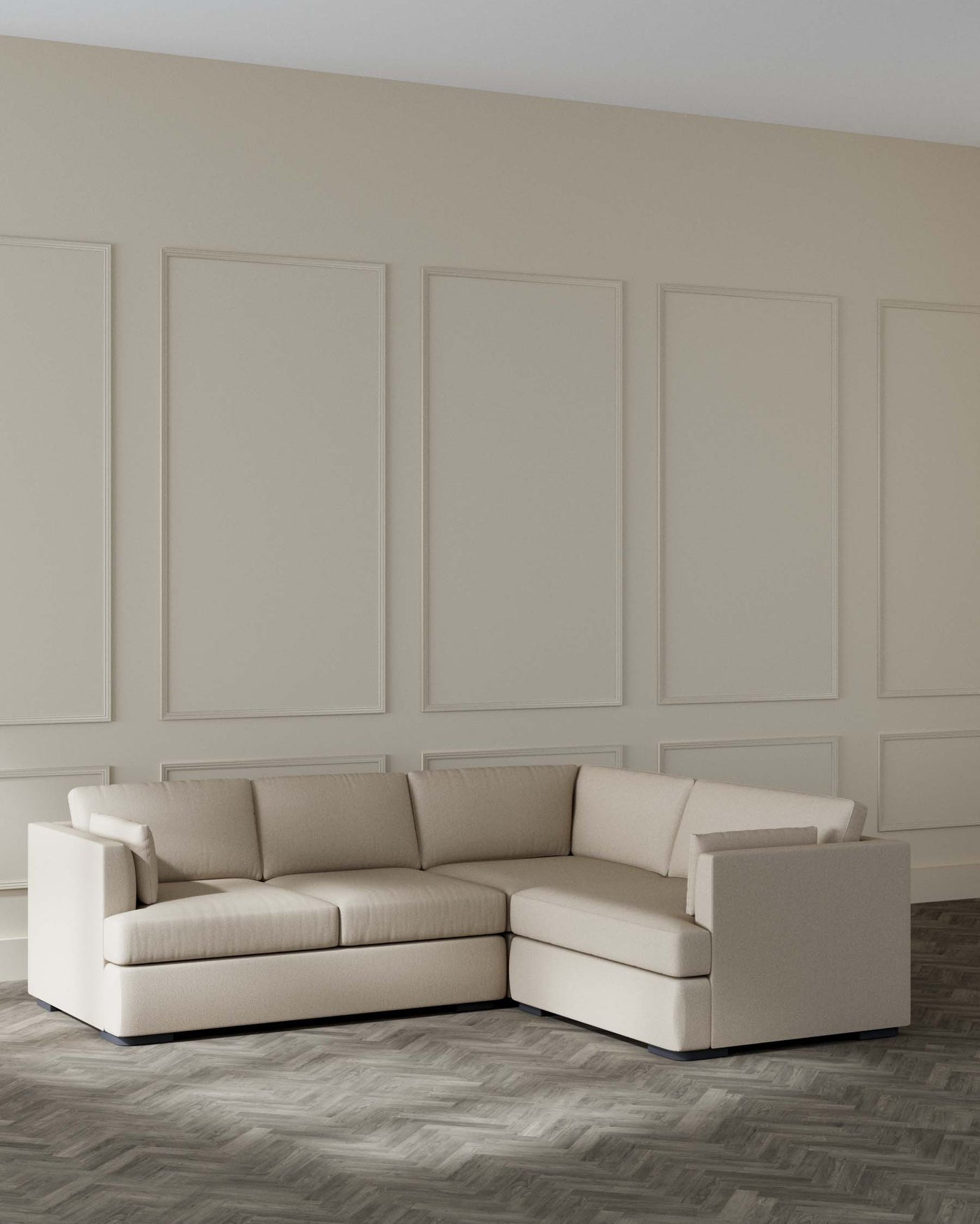 A contemporary beige sectional corner sofa with a minimalist design, featuring clean lines, and plush cushions, set on a sleek, low-profile base in a modern living room with herringbone-patterned wooden flooring and panelled walls.