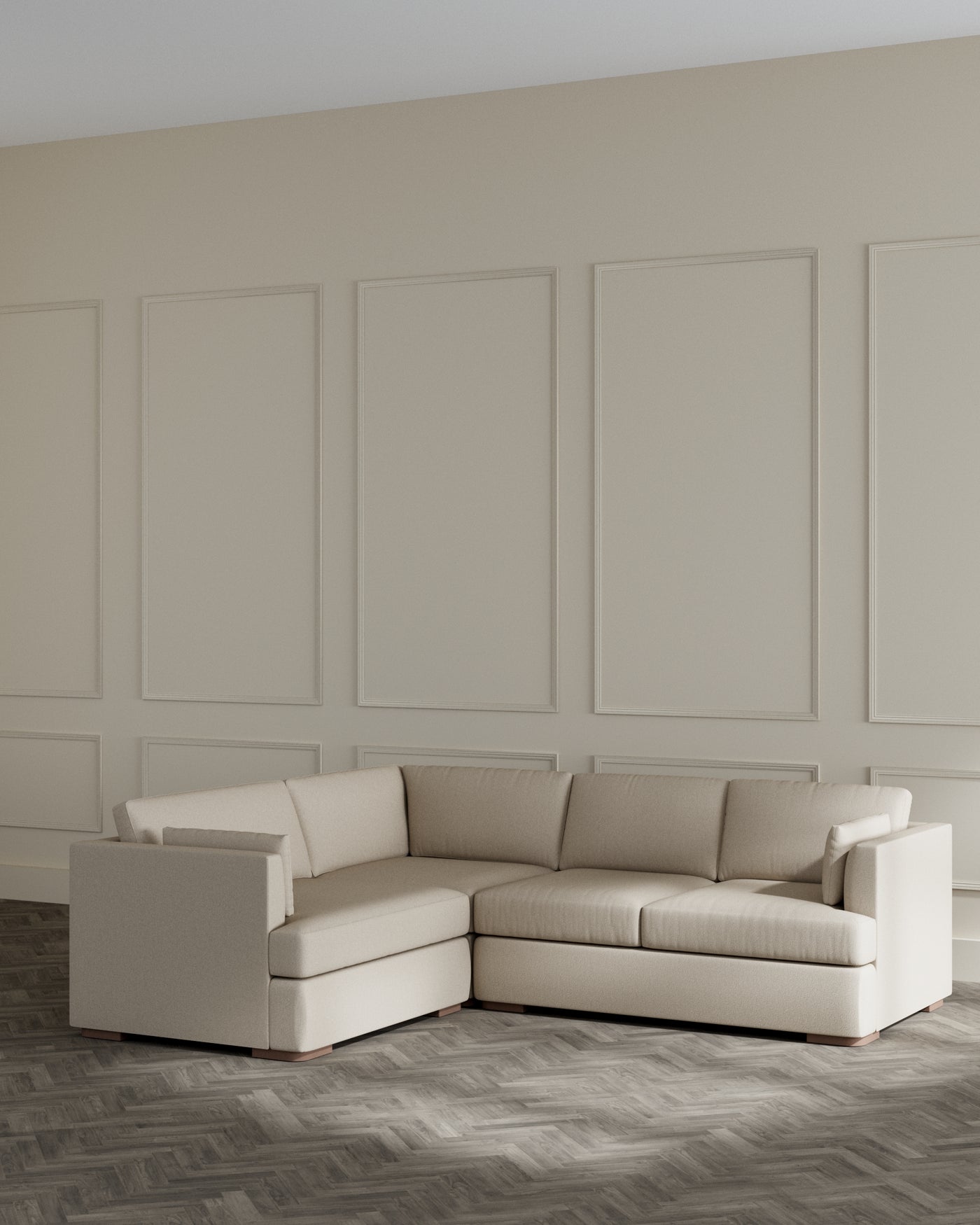Modern beige L-shaped sectional sofa with clean lines and a minimalist design, featuring plush cushioning, subtle tufting detail, and a low-profile silhouette, set against a neutral wall and herringbone wood flooring.