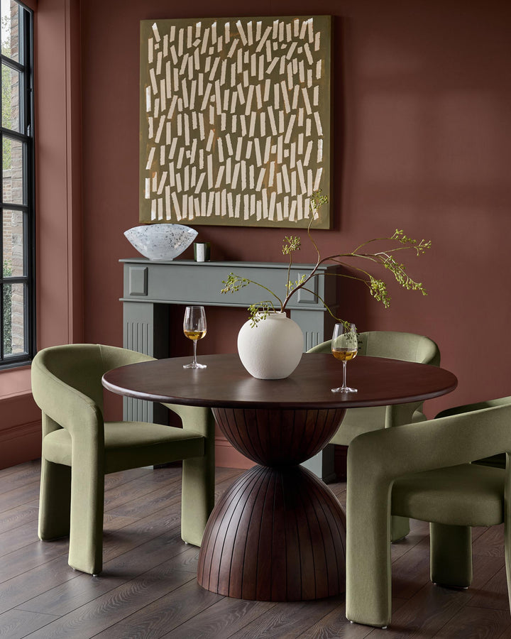 Asher dining chair in olive-green fabric with curved back and cylindrical legs, shown in room setting.