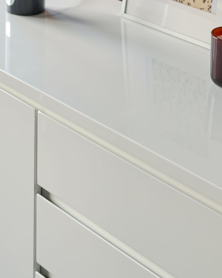 White gloss sideboard with integrated handle detail on drawer front, shown at an angle.