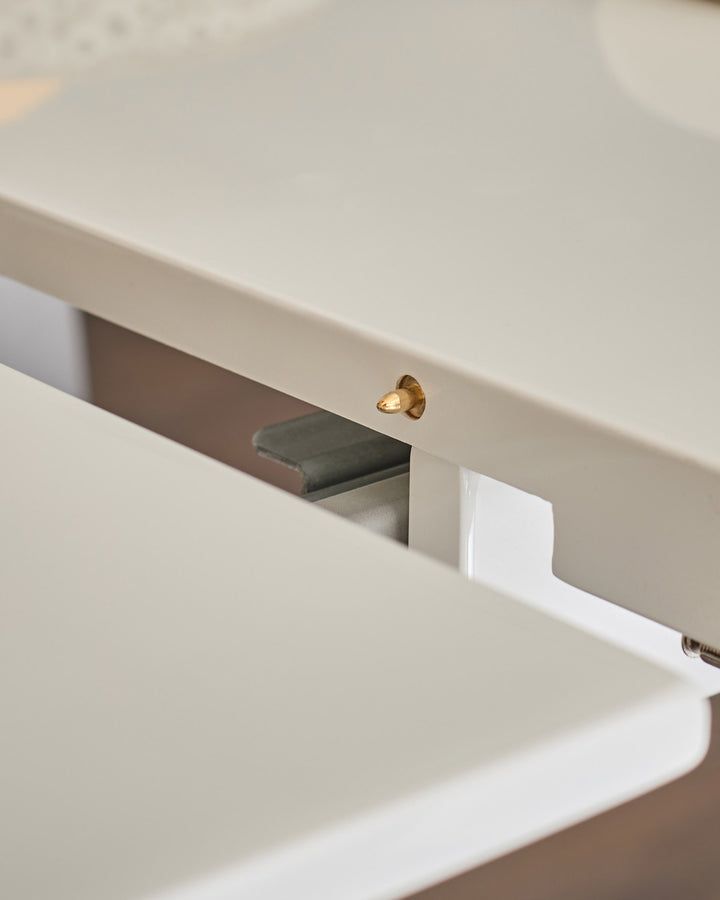 Close-up of brass handle on white extending dining table leaf slot.
