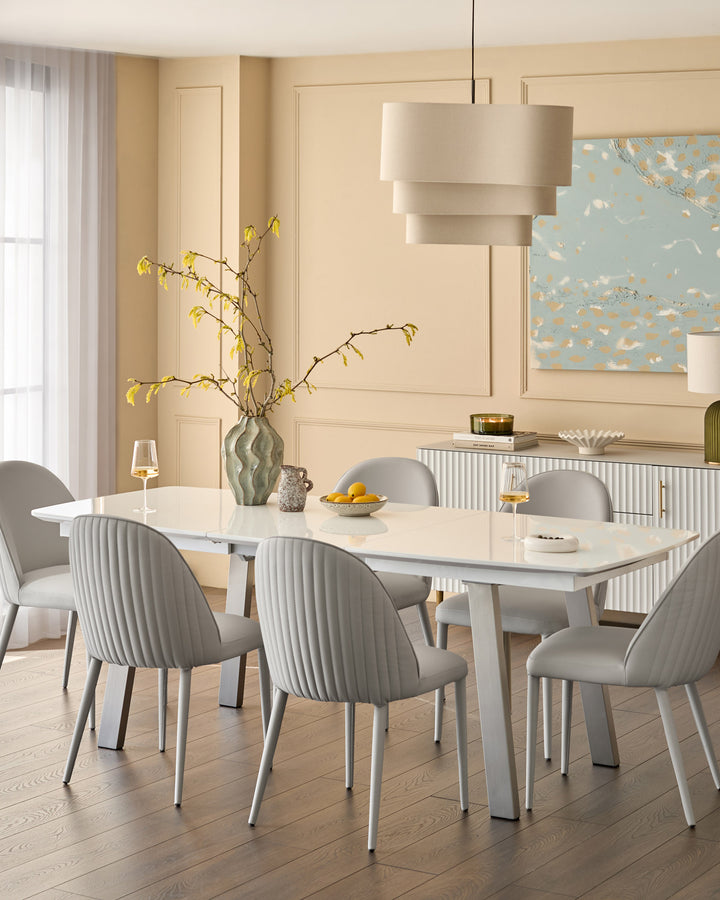 Saylor faux-leather dining chair in light grey, shown in elegant dining room setting with ribbed backrest and metal legs.