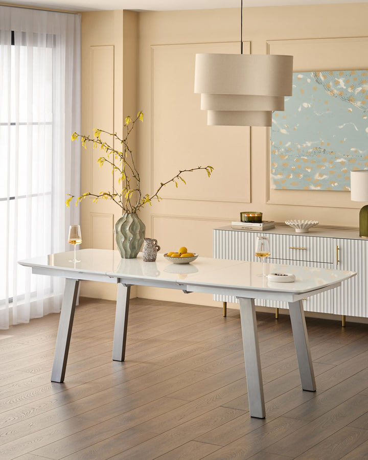 White extending dining table with light wood top and metal legs in modern dining room setting.