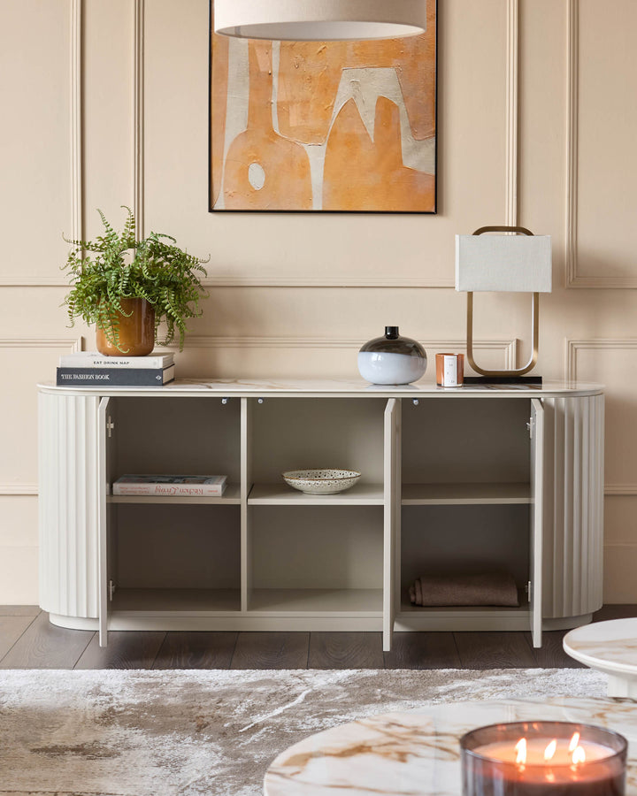 Display cabinet with shelving and fluted doors, topped with decor. Ideal for living room storage and style.