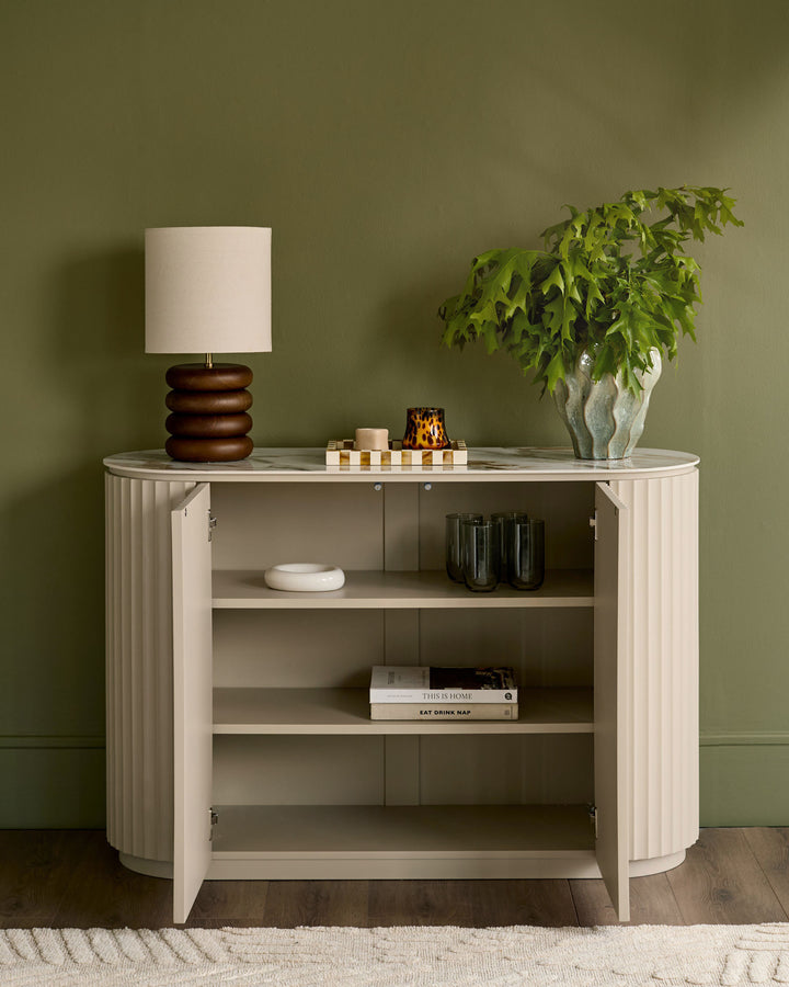 Austin Compact Sideboard in natural ceramic finish with ribbed vertical detailing, open doors, and internal shelving displayed against sage green wall.