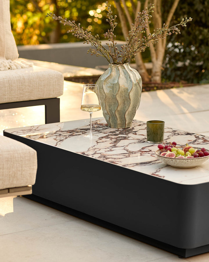Bianco garden coffee table with black base and white Calacatta marble top, styled on outdoor patio with décor.