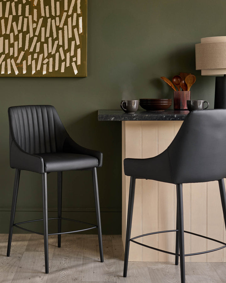 Black faux leather bar stool with vertical stitching, metal legs, and footrest, styled at counter height.