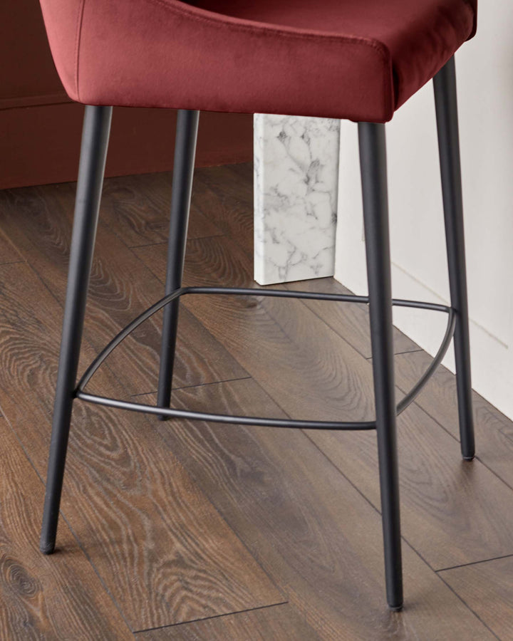 Close-up of a stool with a burgundy seat and black metal legs, showcasing its design and materials.