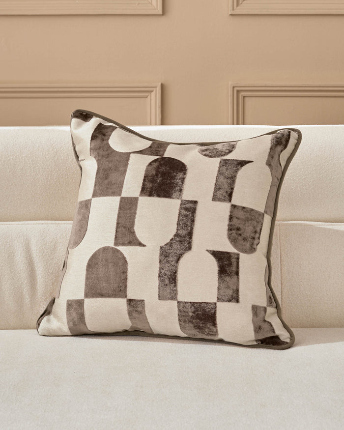 Bridget cushion in chocolate and cream with geometric patterned design, displayed on a neutral sofa.