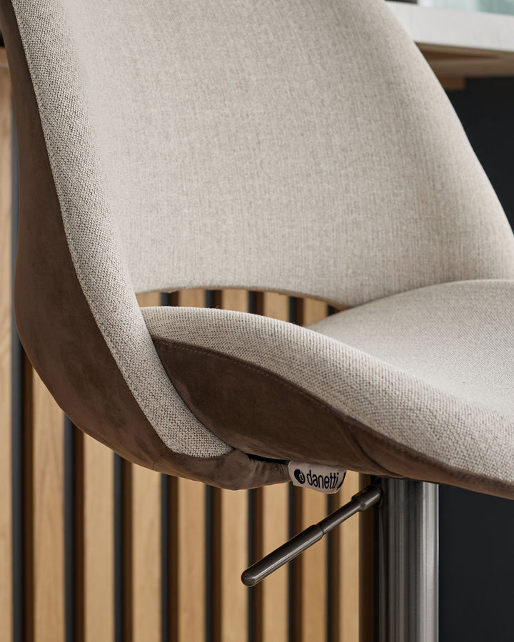 Bronwyn gas lift bar stool in natural fabric and mocha velvet, side angle view showing curved backrest and metal base.