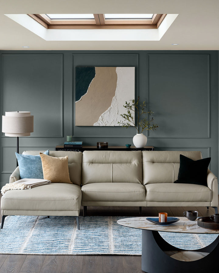 Light grey leather left-hand corner chaise sofa with rolled arms in a modern living room setting.