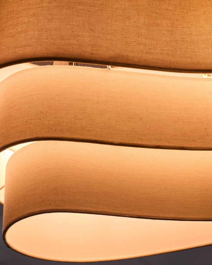 Natural linen shades stacked showing curved cylindrical design and warm cream finish.