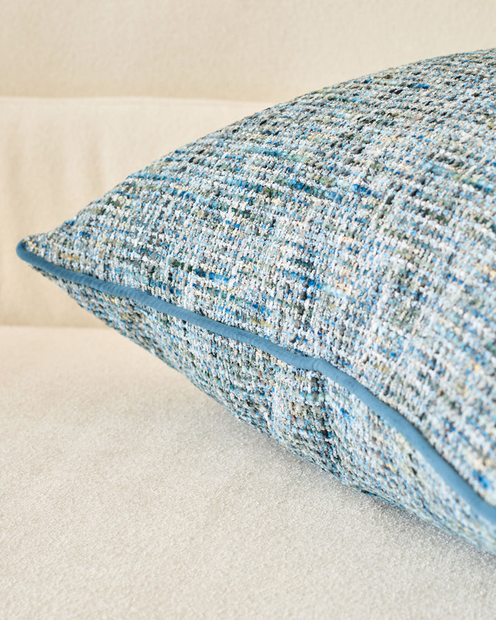Callie Large Cushion in blue textured weave, shown at an angle highlighting its plump, rounded form and piping detail.