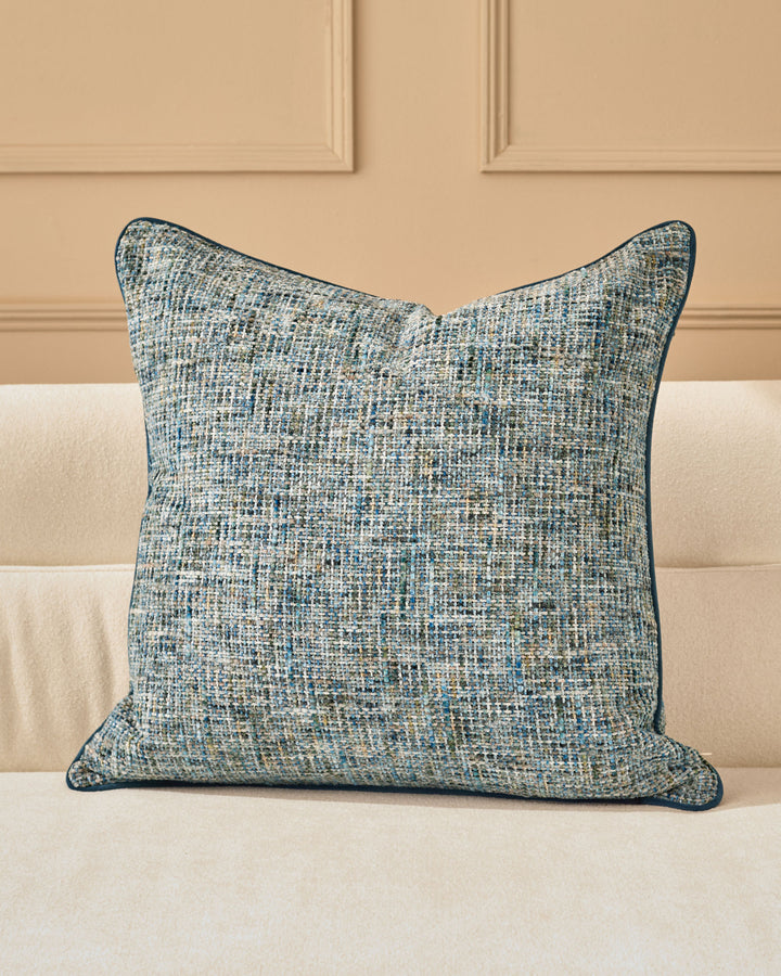 Callie cushion in large blue, featuring a textured woven fabric with blue and neutral tones, displayed on a cream sofa.
