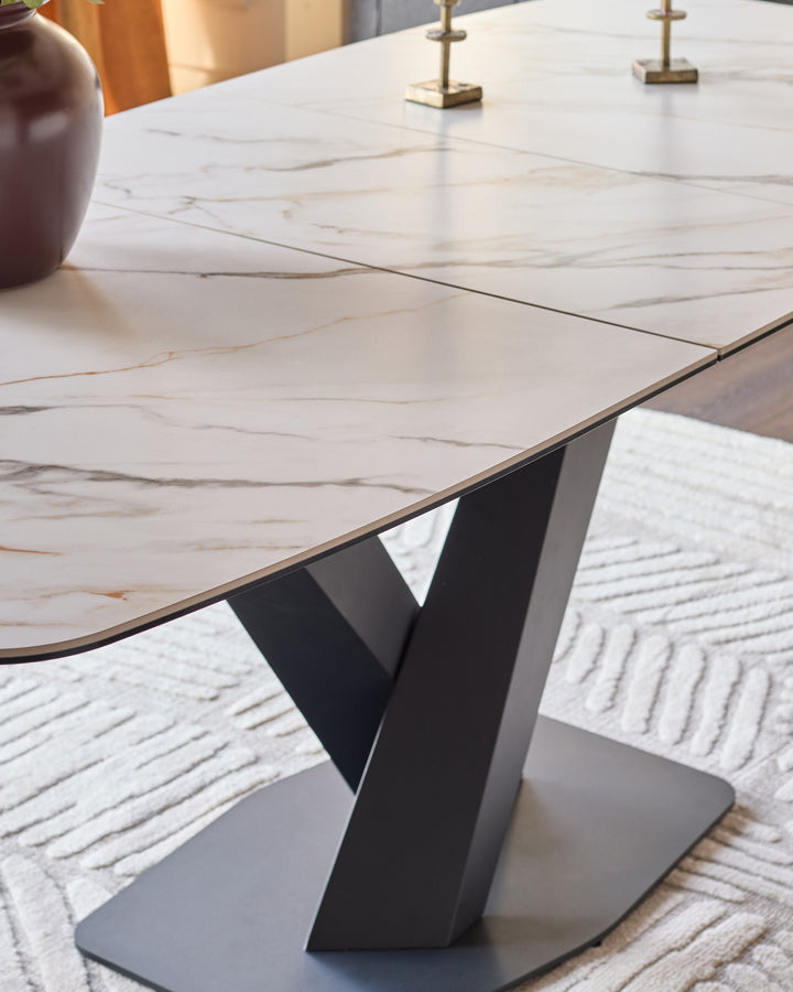 Carter extending dining table with marble-effect ceramic top and black sculptural pedestal base, angled view.