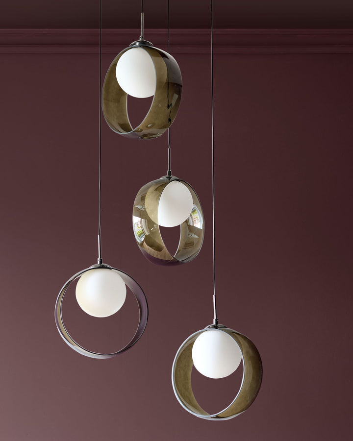 Chloe 4-pendant light with green glass globes and white diffusers, suspended at varying heights against a burgundy wall.