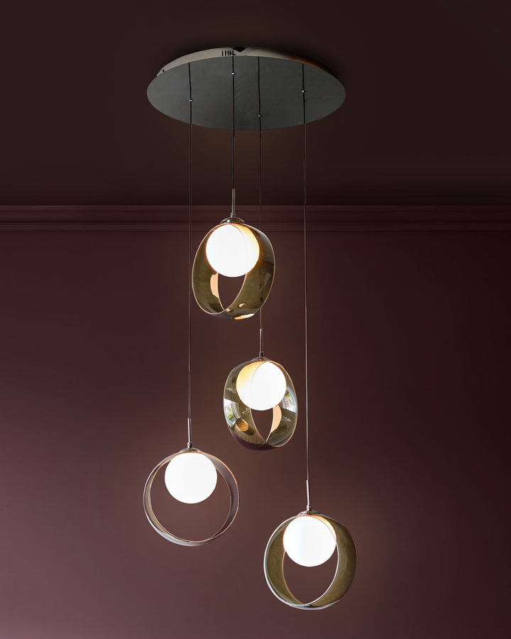 Chloe 4-pendant light with green glass spheres and brass accents, suspended from a ceiling canopy against a burgundy wall.