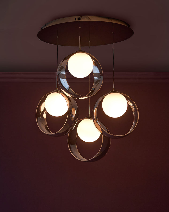 Chloe 4-pendant light with spherical glass shades and chrome finish, suspended from dark canopy against burgundy wall.