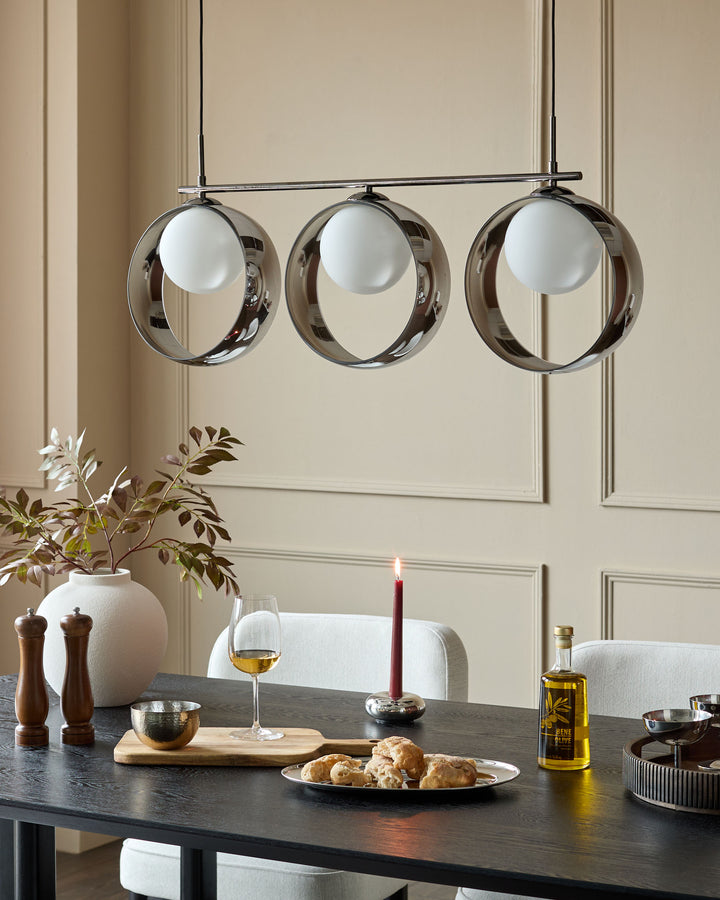 Chloe 3-pendant light with chrome finish and frosted glass globes, suspended above a dining table setting.