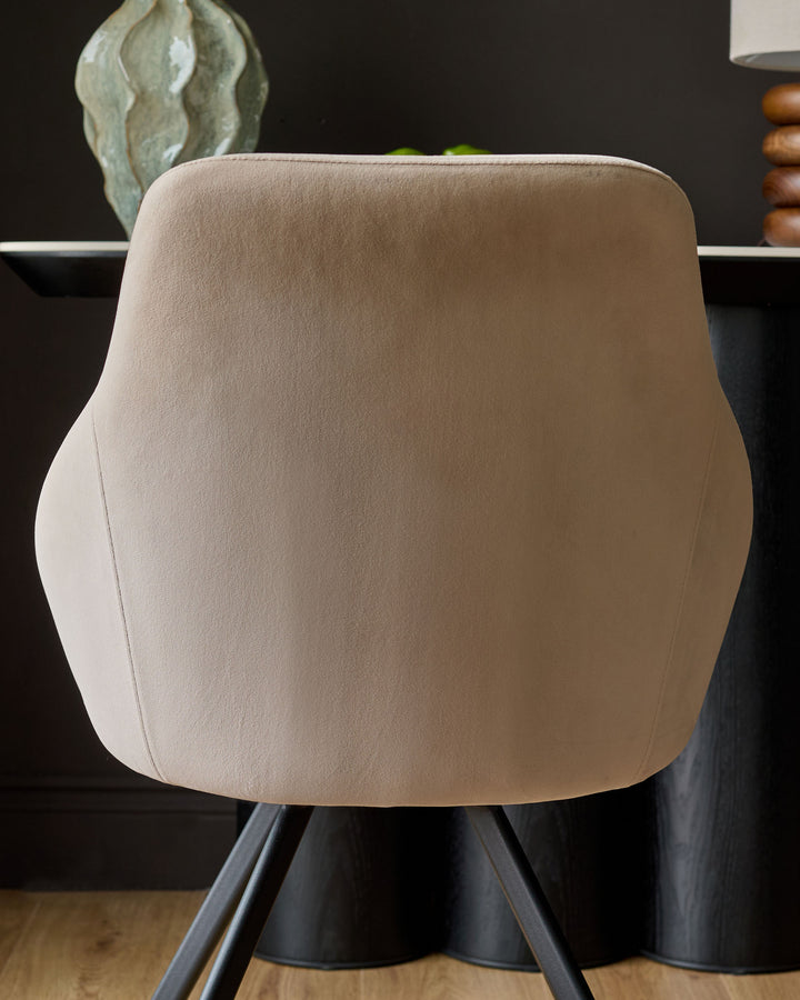 Champagne velvet swivel chair with curved backrest and black pedestal base, shown from behind.