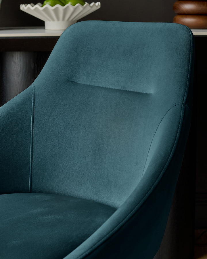 Dark teal velvet swivel chair with curved backrest and armrests, shown at a side angle in a modern interior setting.